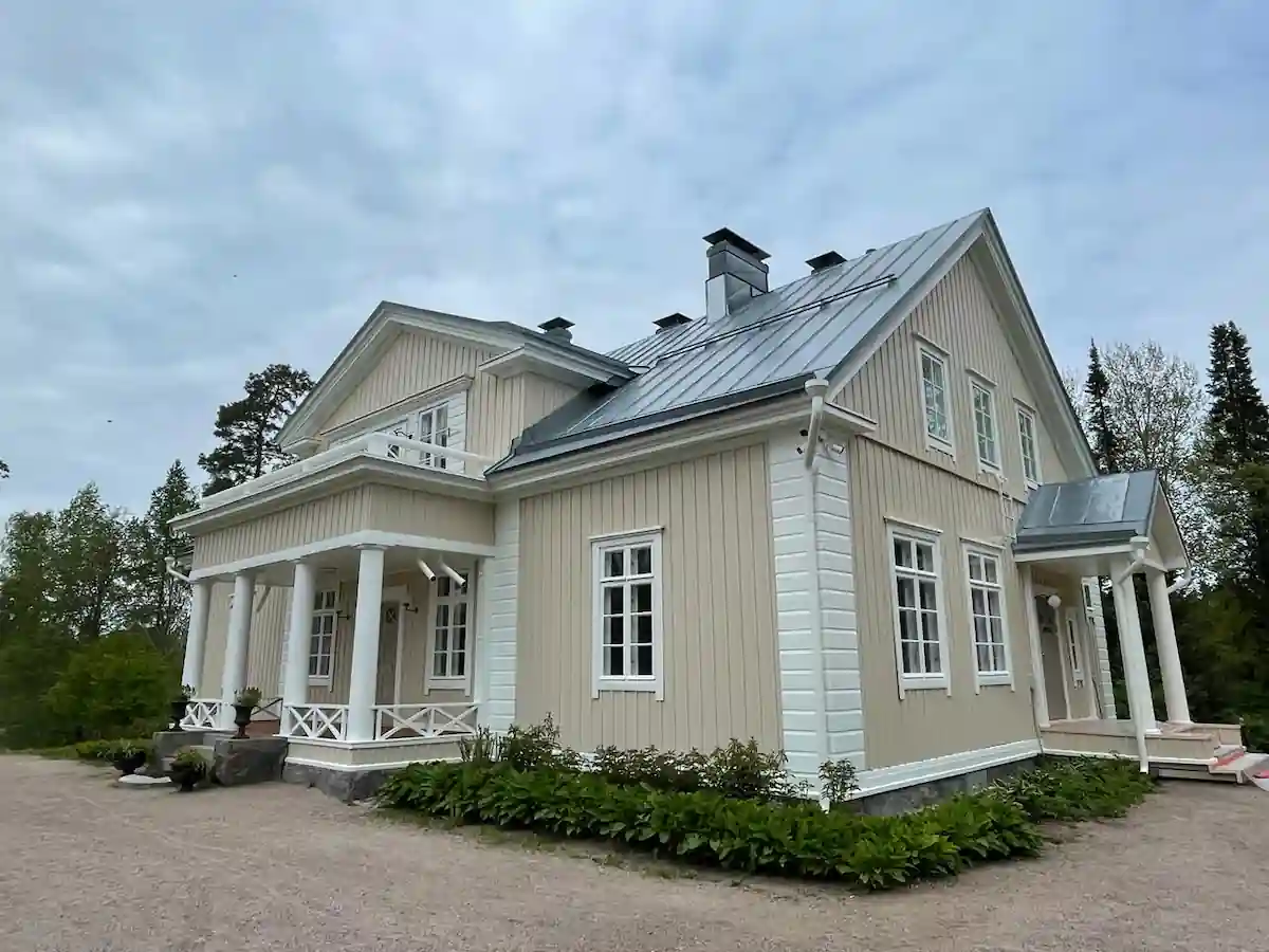 Vaalea kartanomainen puutalo ulkomaalaus jälkeen Pirkanmaalla