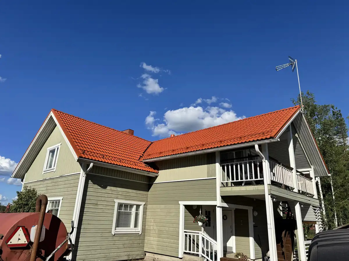 Vihreä puutalo, jonka punainen tiilikatto on juuri pinnoitettu